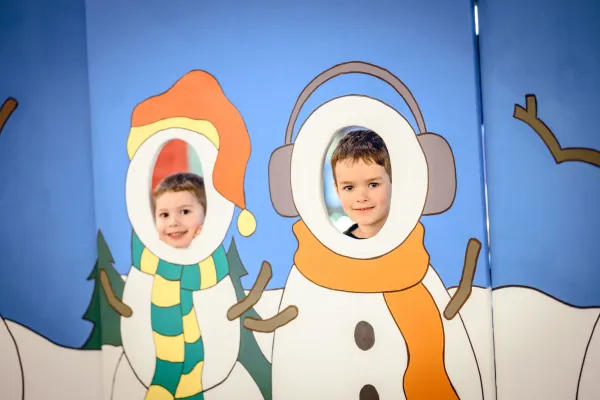 two kids with faces in a snowperson sign